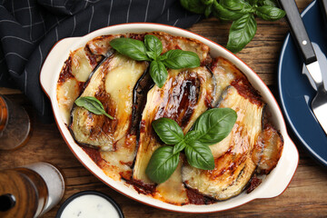 Delicious eggplant lasagna in baking dish on wooden table, flat lay