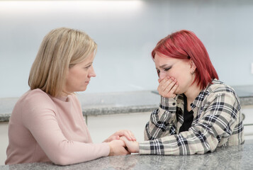 Careful mother and teen girl talk together, worried parent calms crying girl. Teenagers problem...