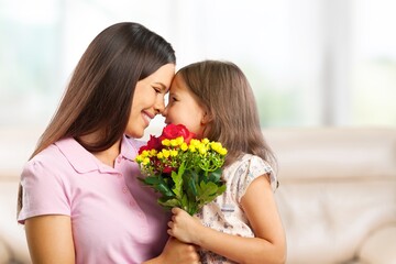 Fototapeta na wymiar Loving little child hugging happy mom and greeting with a bouquet
