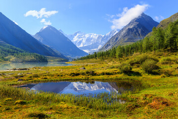 Naklejka na ściany i meble mountain landscape with a lake and the reflection of snow peaks in the water in the valley of the Ak-Kem River of the Altai Mountains with the sacred Belukha Mountain