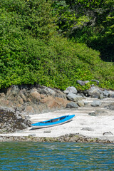 Blue lightweight canoe boat on a shore of ocean bay on sunny day