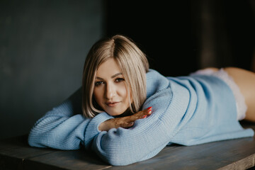 Obraz premium blonde girl in a blue sweater lies on the table
