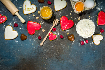 Valentine day sweet cooking background. Baking ingredients and utensils - flour, rolling pin, heart shaped biscuits, eggs. Making cute Valentine`s sweet gift. Top view copy space on dark background