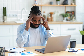 Obraz premium African American businessman freelancer suffering from severe headache after working at the computer for a long time, migraine, emotional stress. Man massaging his whiskey