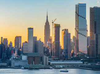 Naklejka premium Stunning sunrise over Manhattan skyline with saturated colors and sun rays camping from the sun.
