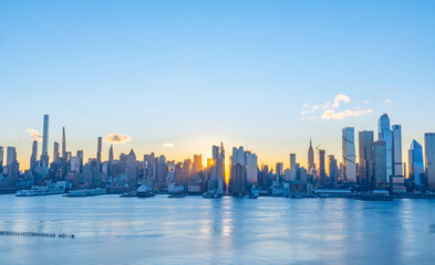 Fototapeta na wymiar Stunning sunrise over Manhattan skyline with saturated colors and sun rays camping from the sun.