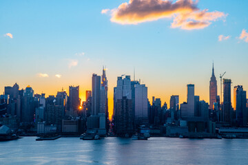 Stunning sunrise over Manhattan skyline with saturated colors and sun rays camping from the sun.