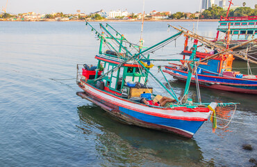 Fototapeta na wymiar In the evening, colorful fishing boats are securely tied down directly at the pier with seaman's ropes and knots