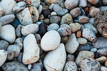 Stones of different shapes, sizes and colors on the seashore, close-up. Background of sea stones.