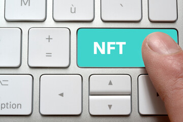 Un homme appui sur la touche de son clavier nft afin d'acheter un fichier numérique unique