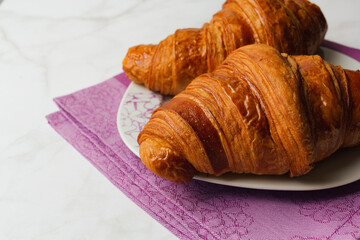 Close up of croissants isolated over marble background. Delicious breakfast or snack with selective focus and copy space.