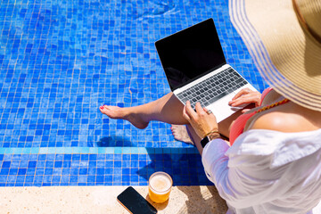 Woman using laptop computer by the pool