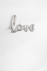 the word love hanging on a wall in silver balloon letters