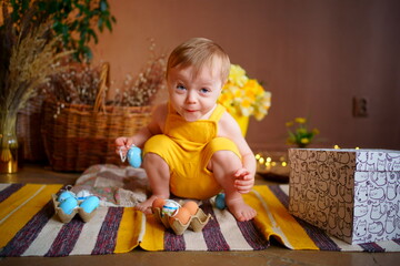 baby with easter eggs in yellow jumpsuit. High quality photo