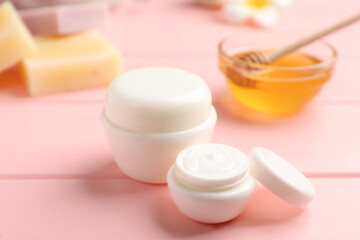 Fototapeta na wymiar Jars of cream with natural beeswax component on pink wooden table, closeup