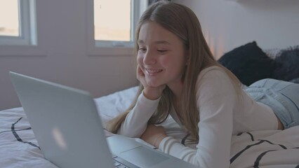 Nice teenage girl using a computer in her bedroom.	

