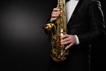 Naklejka premium Saxophonist Guy in Sunglasses Plays the Tenor Saxophone, Musician Blows the Saxophone. Selective Focus on Bell of Saxophone. Blurred Background, Neon Light. High quality photo