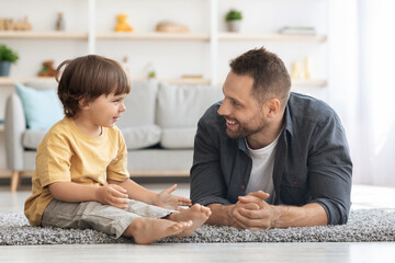 Dad and son communication. Positive little boy talking with his cheerful daddy, carrng father...
