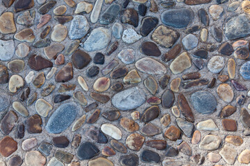 Stones of various shapes and colors are laid out on the road as a sidewalk close-up.