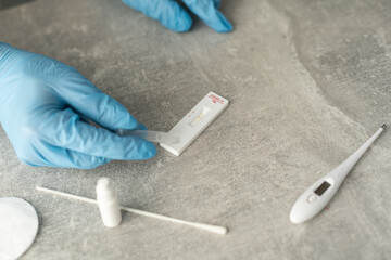 senior woman hands using lancet on finger at home to check blood sugar level, glucometer and sugar cubes on wooden table close up, diabetes concept, elderly health care, sunny morning