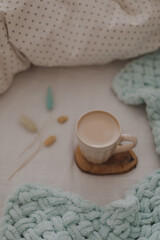 Cup of fresh coffee in bed, morning mood. Linen cotton textile bedclothes. Organic and natural linen. Cozy bedroom interior. Beautiful light.