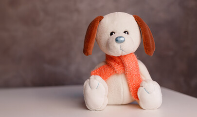 Soft toy white dog for kids sitting on a gray background, cute baby dog