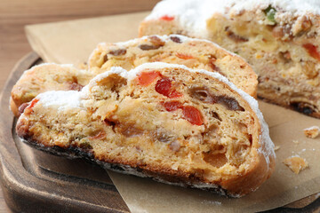 Traditional Christmas Stollen with icing sugar on wooden board, closeup