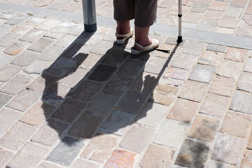 Shadow and legs of an elderly woman with a walking aid