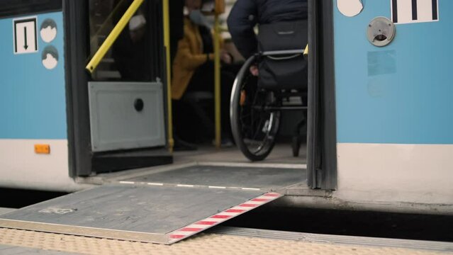 Person with a physical disability enters public transport with an accessible ramp