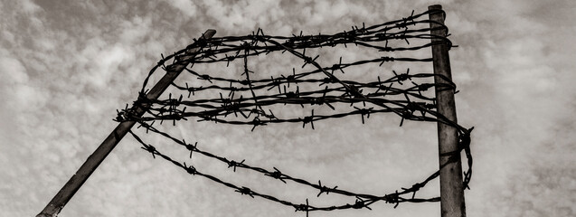 Horizontal banner or header with barbed wire on the concrete fence  - Concept of imprisonment and...