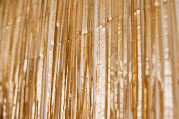 Gold tinsel party backdrop decoration hanging on the wall. Golden background for ids birthday party...