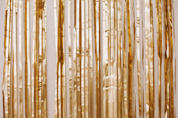 Gold tinsel party backdrop decoration hanging on the wall. Golden background for ids birthday party...