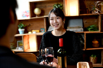 笑顔でお酒と食事を楽しむアジア人女性と男性（カップル）