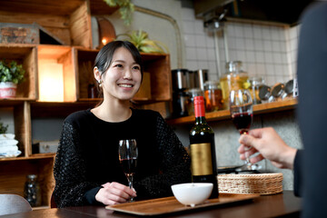 笑顔でお酒と食事を楽しむアジア人女性と男性（カップル）