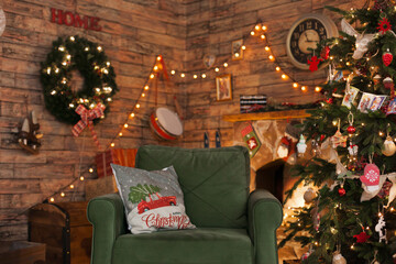 Obraz premium Cozy living room with armchair and fireplace decorated for winter holiday season with a christmas tree and lights. Interior of a room on christmas holiday season.