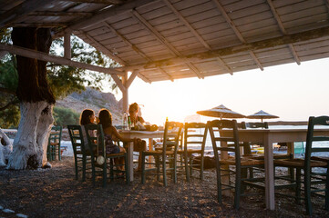 Family enjoying dinner in a restaurant on the beach at sunset.