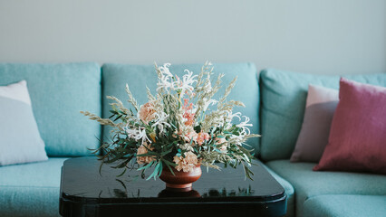Couch, cushions, black table and a flower arrangement