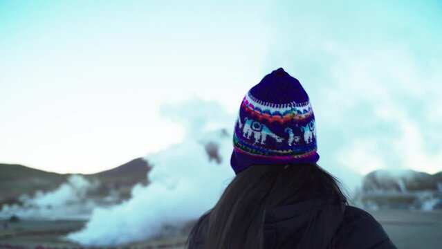 Mujer sonriente en geiser con niebla y mucho humo en el Tatio Atacama, Chile