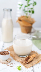 Flax seeds milk in glass on sackcloth, bottle, linen seeds, mint plant and leaf