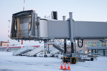 Empty passenger boarding bridge and air-stairs at winter airport apron