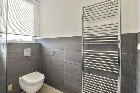 Interior of restroom with heated towel rails and toilet bowl