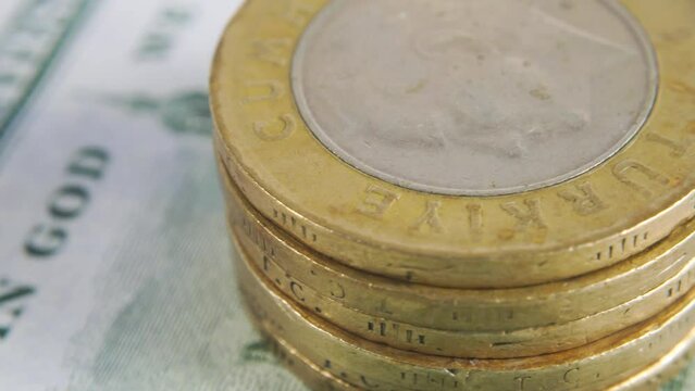 A stack of Turkish Lira against the background of US $ 100 banknotes. Turkish Lira coins on Cuamerican banknotes. Rotating money background lira and dollars. Turkish lira coins rotate.