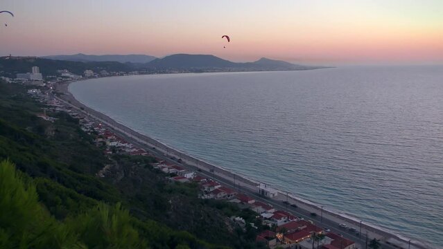 Men on a paraglider against the backdrop of the sea landscape and sunset sky.