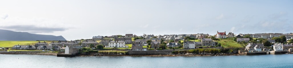 Fototapeta na wymiar Panoramic photograph of Stromness, Orkney, Scotland - Full view of the village viewed from the deck of the ferry.