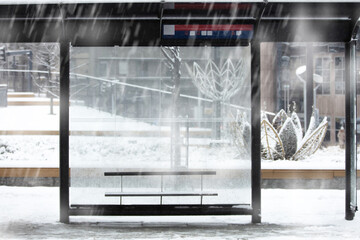 Empty urban bus stop during heavy witner snowfall.