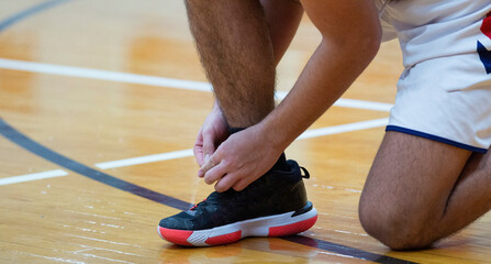 Basketball player tyring his shoes during a game - obrazy, fototapety, plakaty
