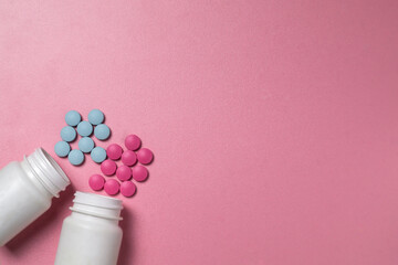 Blue and pink pills spill out of white jars