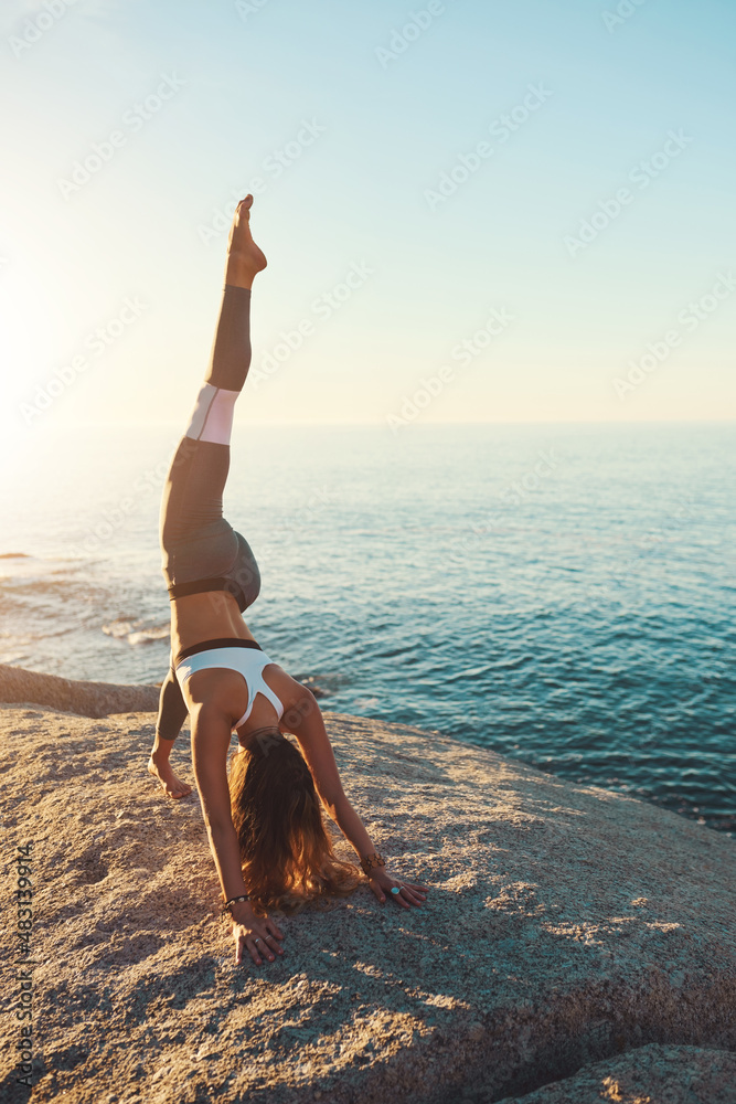 Poster Yoga is like magic. Shot of an athletic young woman practicing yoga on the beach.