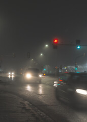 cars driving on city street in foggy night