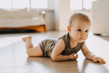 8 months old baby crawling on the floor at home. - Powered by Adobe